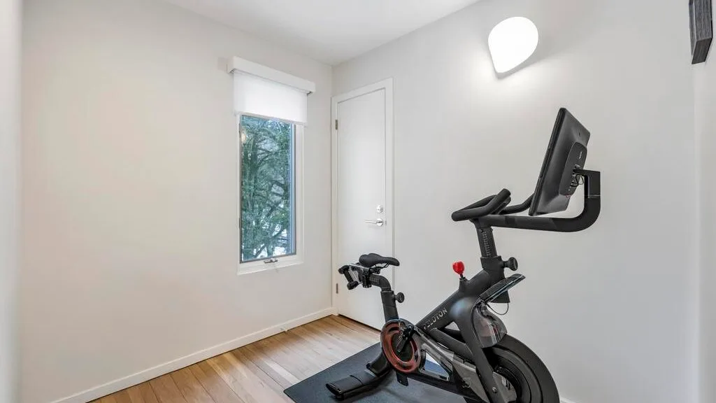 A bright exercise room with a stationary bike beside a window.