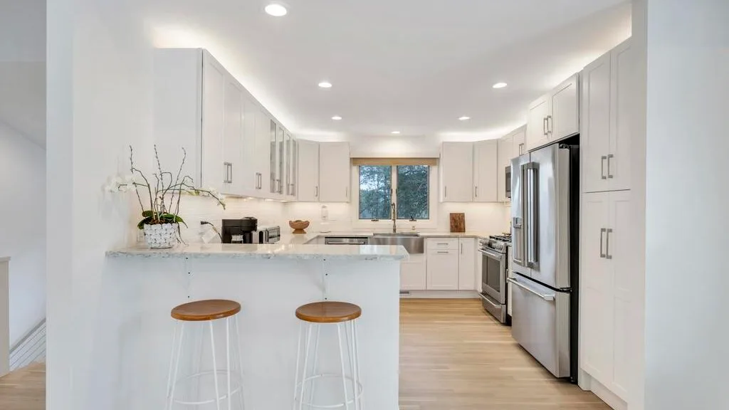 A bright kitchen with white cabinets, an island, and stainless steel appliances.