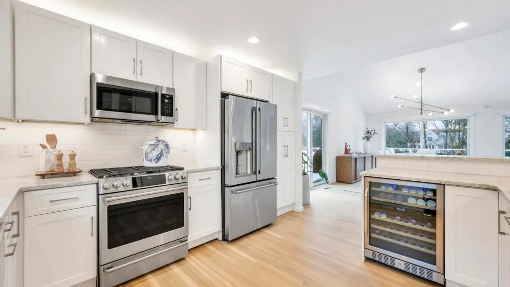 A bright kitchen with white cabinetry, stainless steel appliances, and a central island.