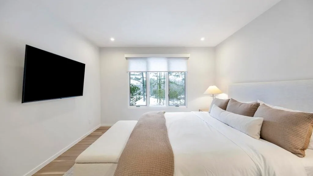 A bright bedroom with a large bed and a wall-mounted television.