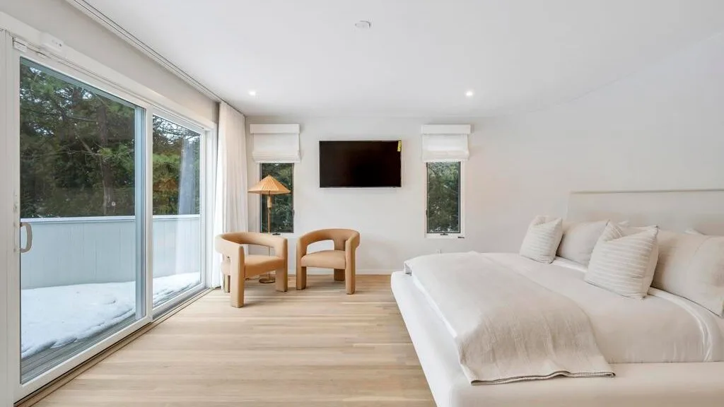 A bright bedroom with a large bed and sliding glass doors.