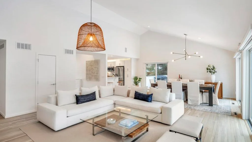 A bright open-plan living and dining area with a sectional sofa and large windows.
