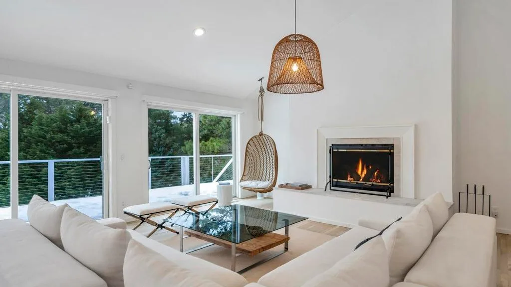 A bright living room with seating around a glass coffee table and a fireplace.