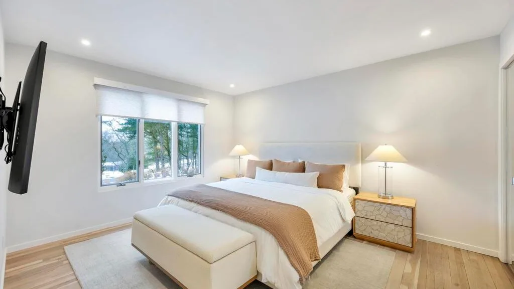 A bright bedroom with a bed, bedside tables, and a window.