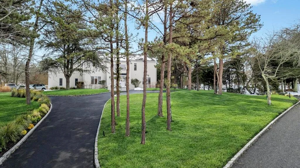 A landscaped green lawn with trees lies between two paved paths.