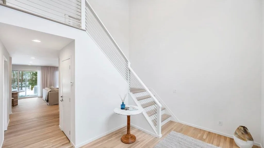 A bright open interior with a white staircase and a small round table.
