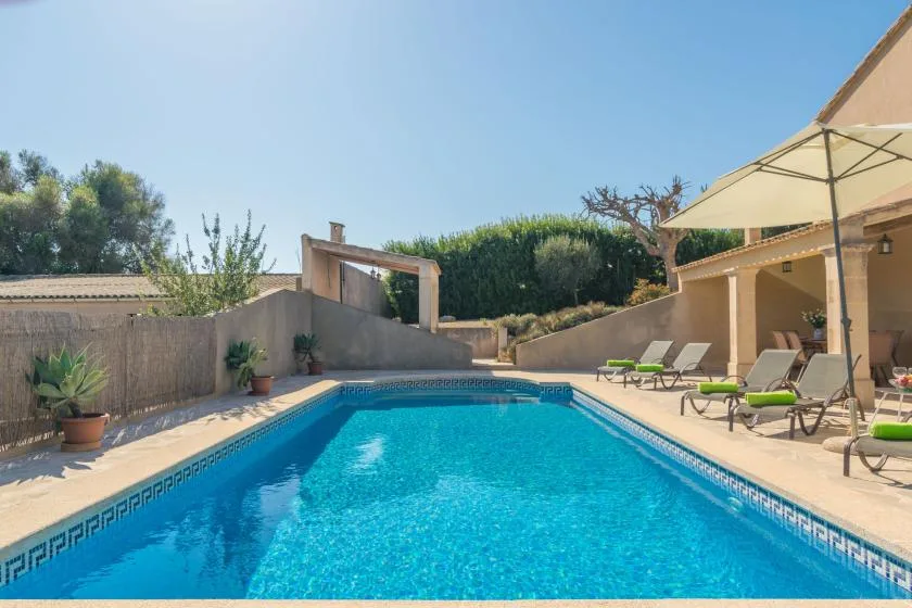 An outdoor swimming pool beside a patio with lounge seating.