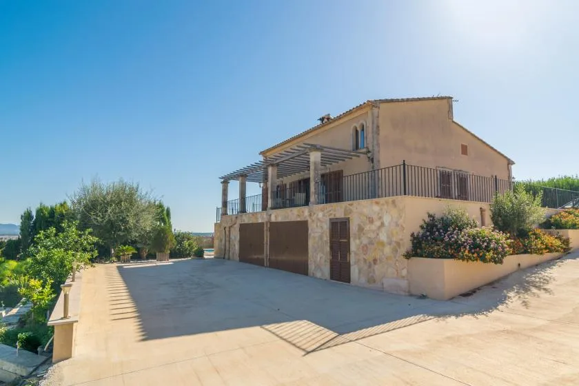 A large house with a balcony and driveway under a clear blue sky.