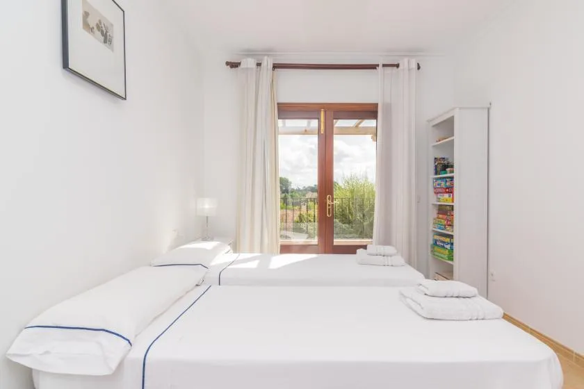 A bright bedroom with white bedding and glass doors opening onto a balcony.