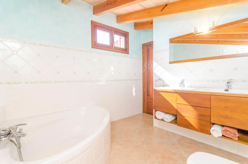 A bathroom with a bathtub, wooden vanity, and large mirror.