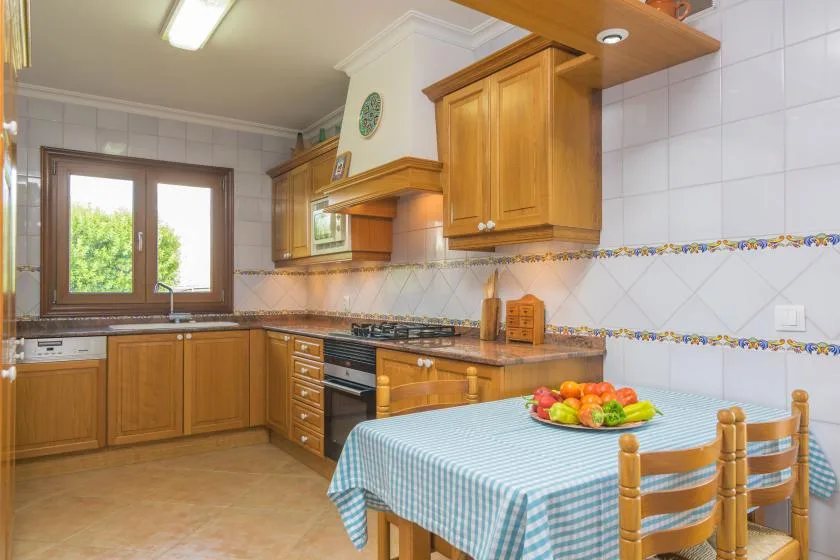A warm-toned kitchen with wooden cabinets and a checkered tablecloth.