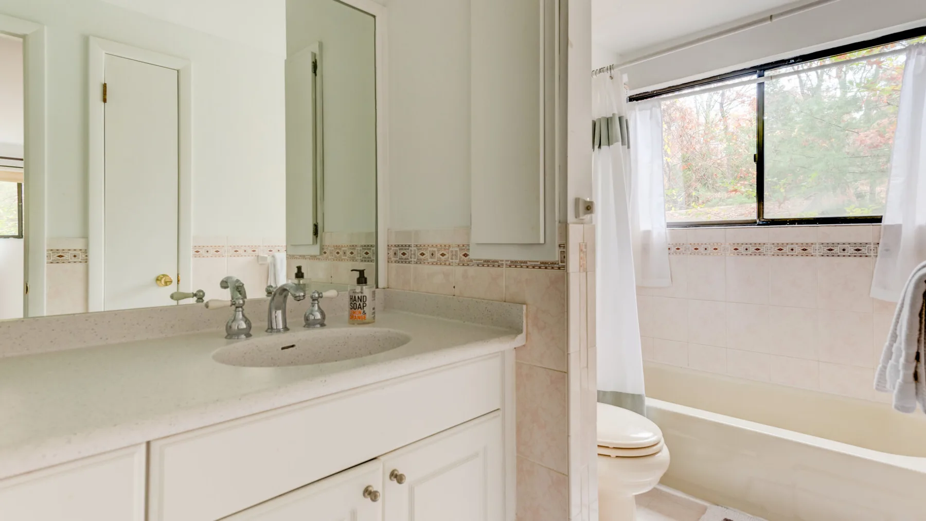 Un baño luminoso con un amplio lavabo y una ventana sobre la bañera.