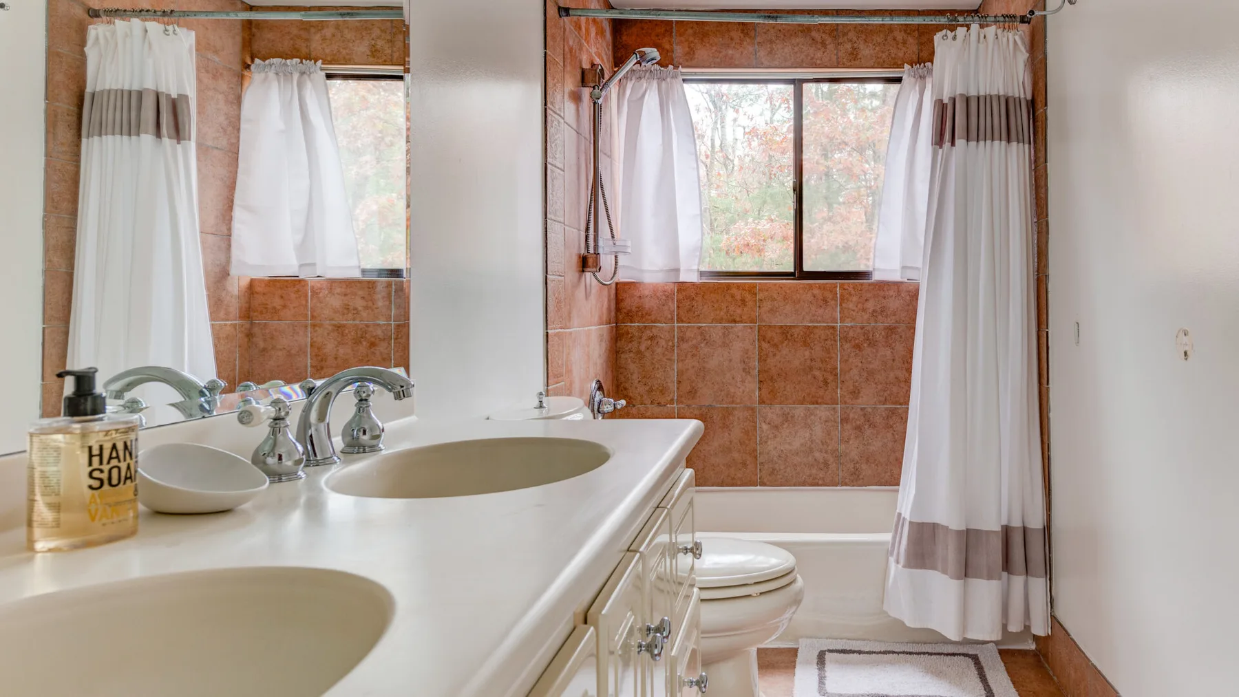 Un baño con un lavabo doble y una ducha junto a una ventana.