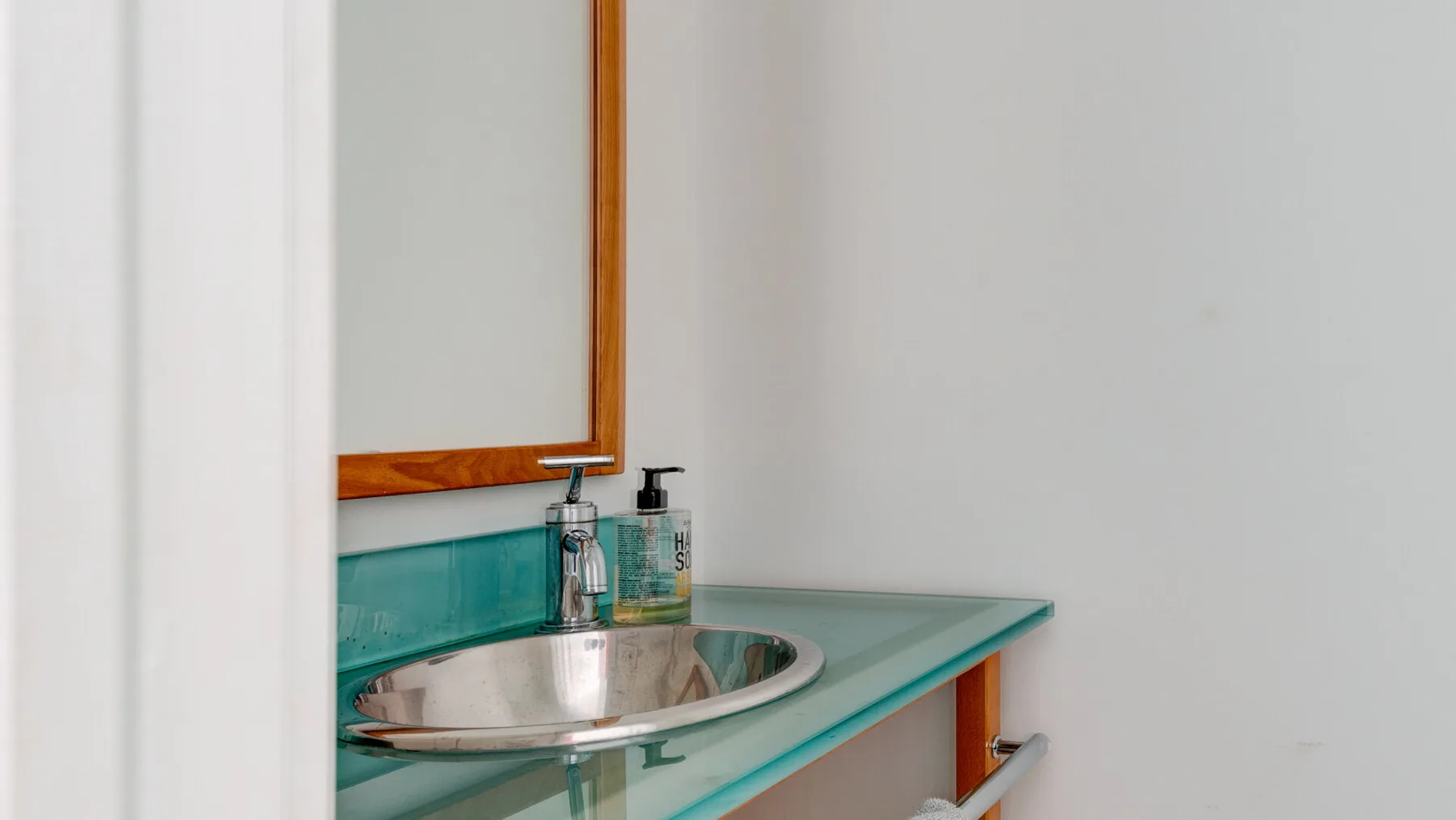 Un tocador de baño con lavabo, espejo y encimera turquesa.