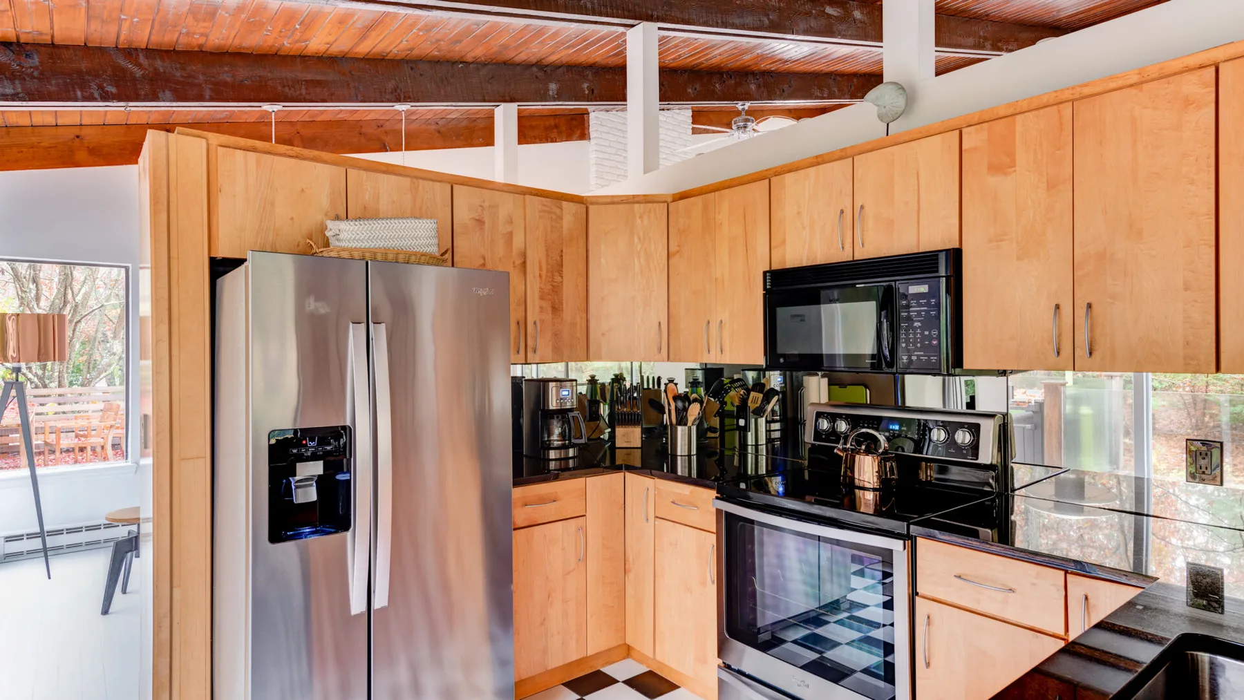 Una cocina revestida de madera con refrigerador de acero inoxidable y electrodomésticos negros.