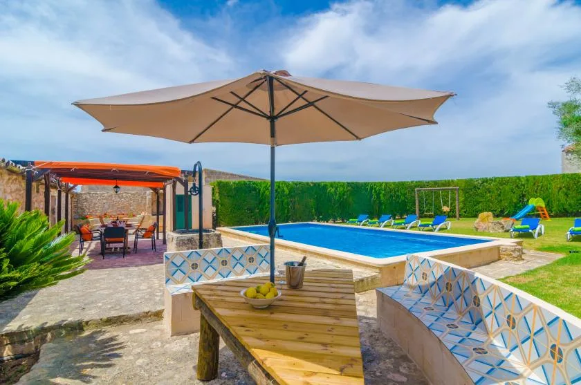 Una zona de piscina al aire libre con una sombrilla grande y asientos.