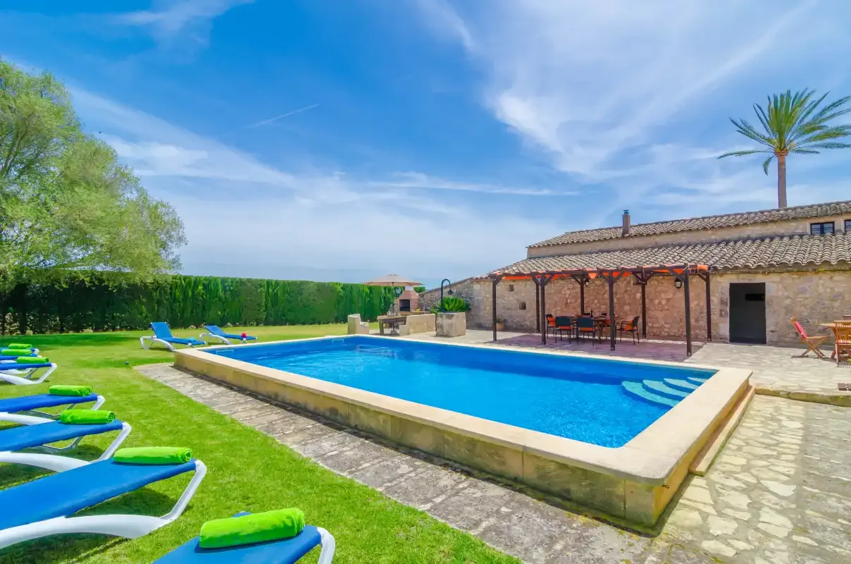 Una piscina al aire libre está junto a un patio de piedra y un edificio bajo.
