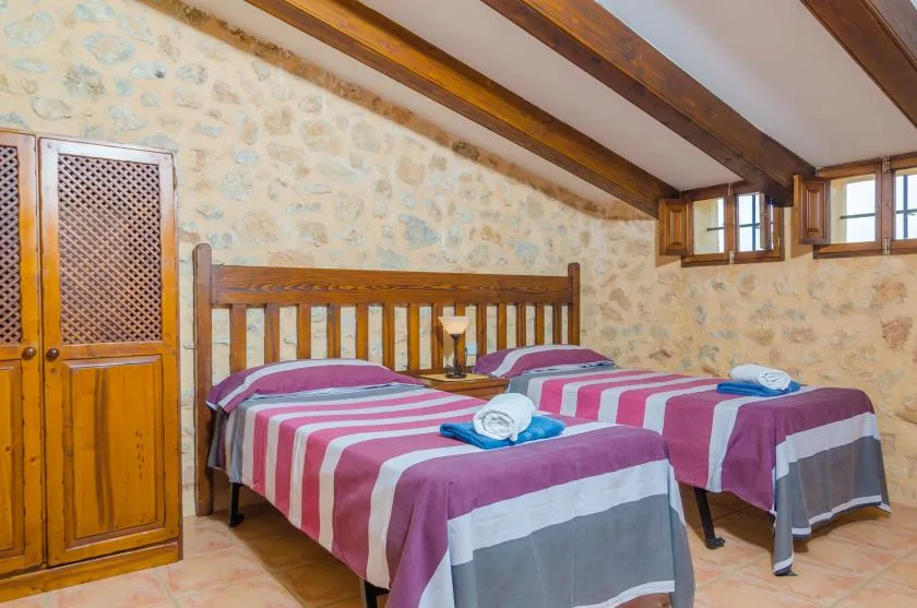 Un dormitorio con dos camas cubiertas con ropa de rayas bajo vigas de madera.