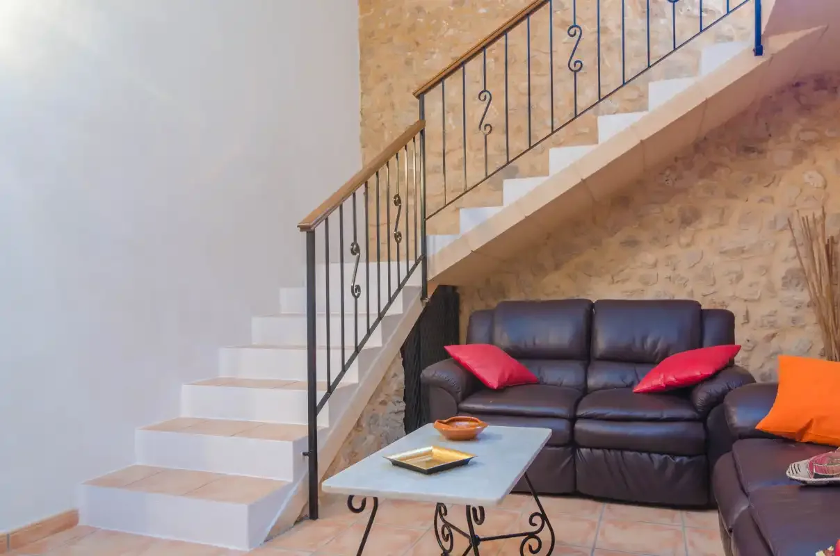 Una sala de estar con asientos oscuros bajo una escalera y una mesa pequeña.