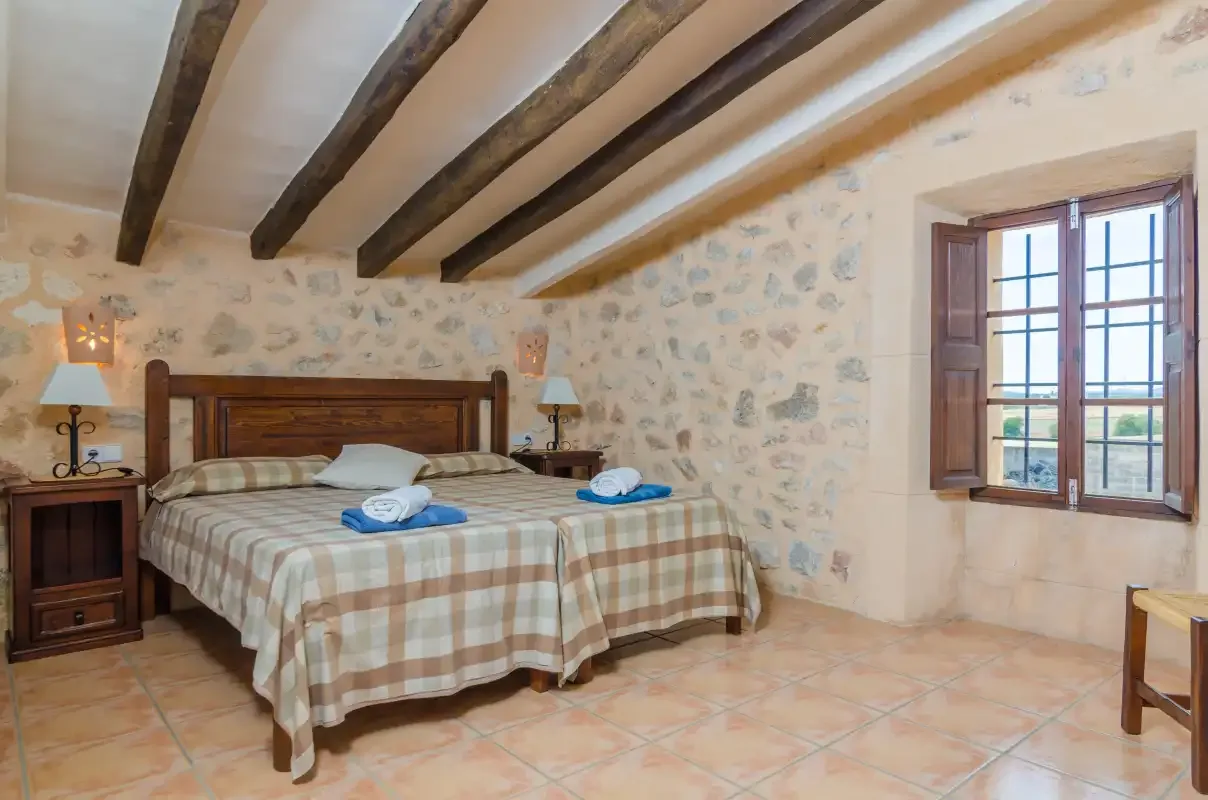 Un dormitorio rústico con una cama doble y una ventana con vistas al campo.