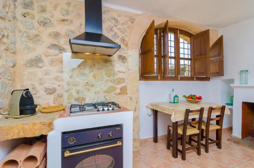 Una cocina rústica con una estufa, una pared de piedra y una mesa de madera.