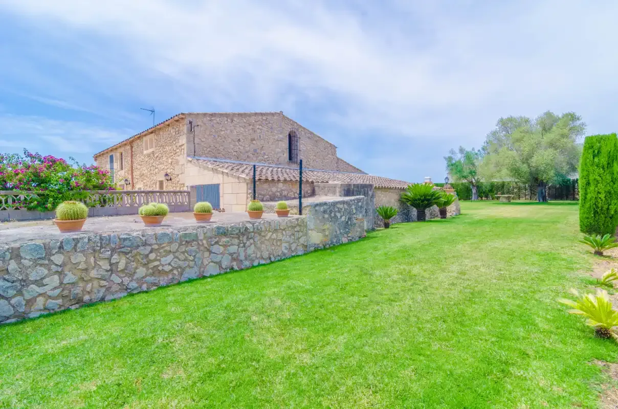 Un edificio de piedra da a un césped verde y un muro bajo de jardín.