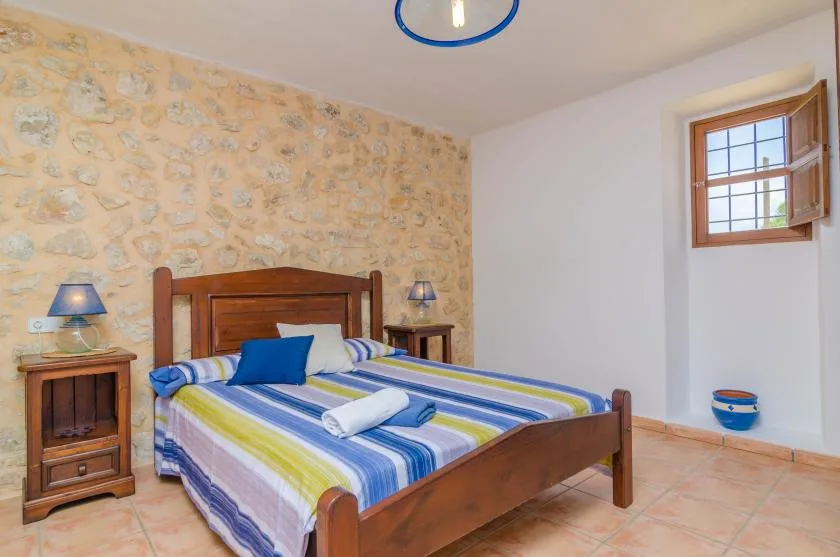 Un dormitorio con una cama de madera y ropa de cama a rayas azules, verdes y blancas.
