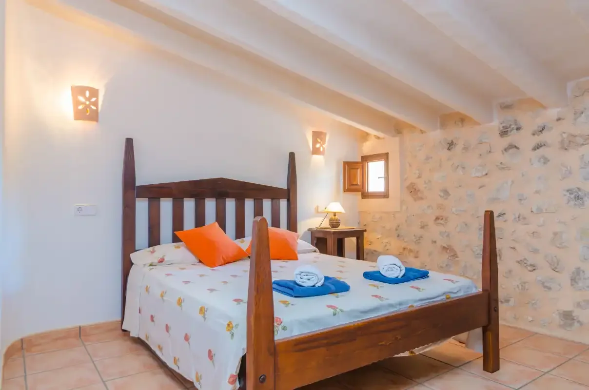 Un dormitorio con una cama de madera, almohadas de colores y una pequeña mesa de noche.