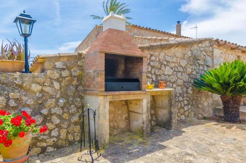 Un patio de piedra cuenta con una barbacoa de ladrillo integrada y plantas en macetas.