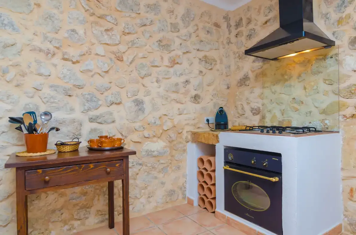Una cocina rústica con estufa y horno junto a una pared de piedra.