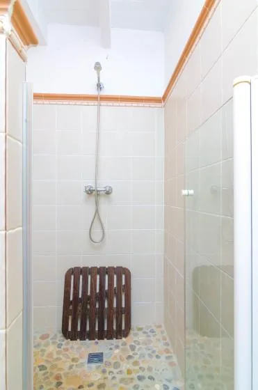 Zona de ducha alicatada con una ducha de pared y suelo de patrón de guijarros.
