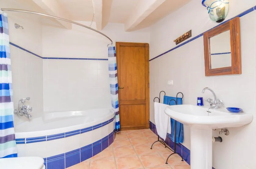 Un baño alicatado con bañera curva, lavabo y puerta de madera.