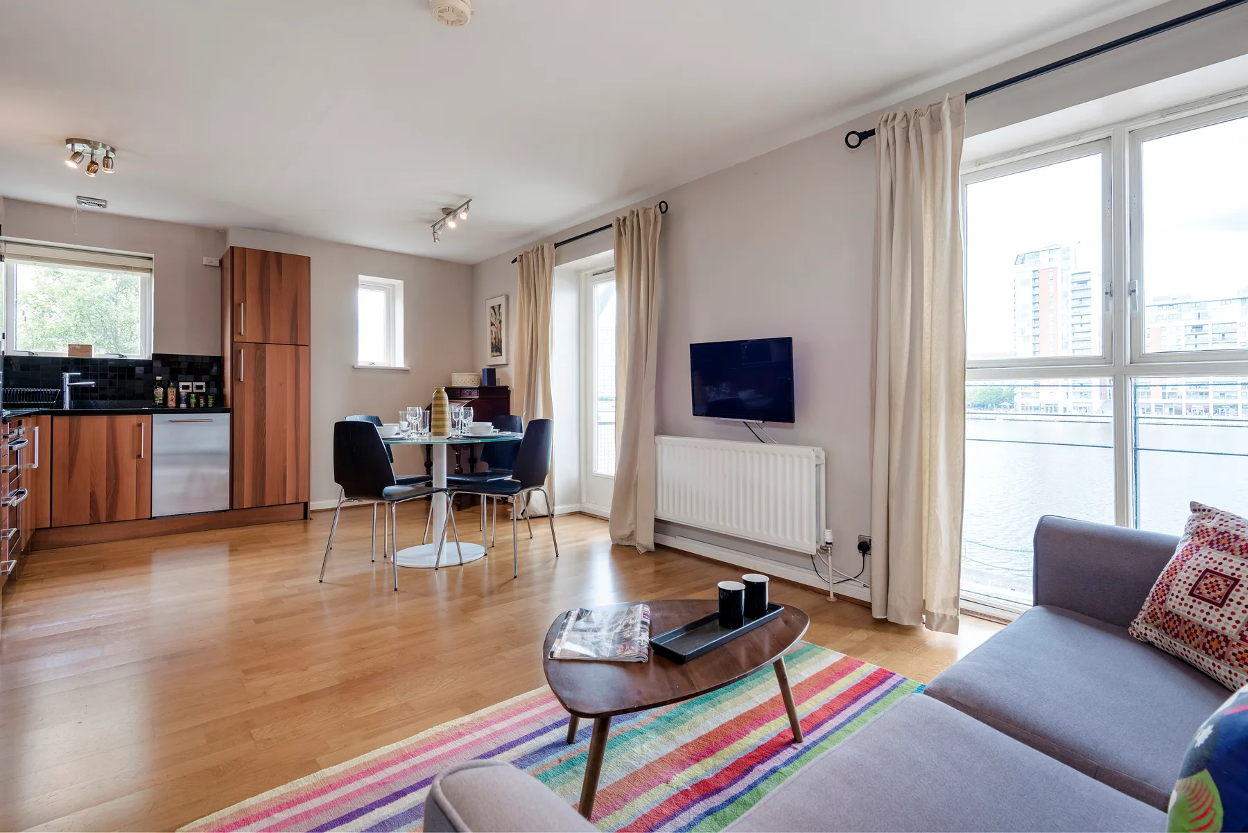 An open-plan living and dining area with a kitchen and colorful rug.