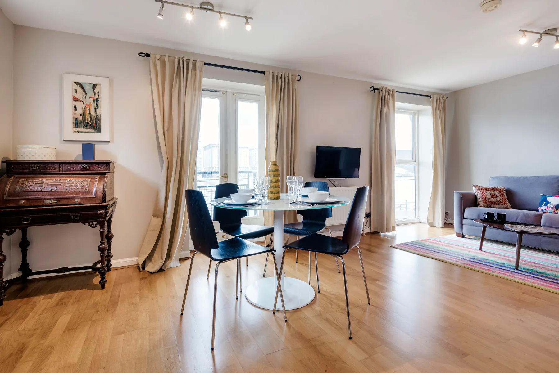 A bright living and dining area with a table, seating, and a piano.