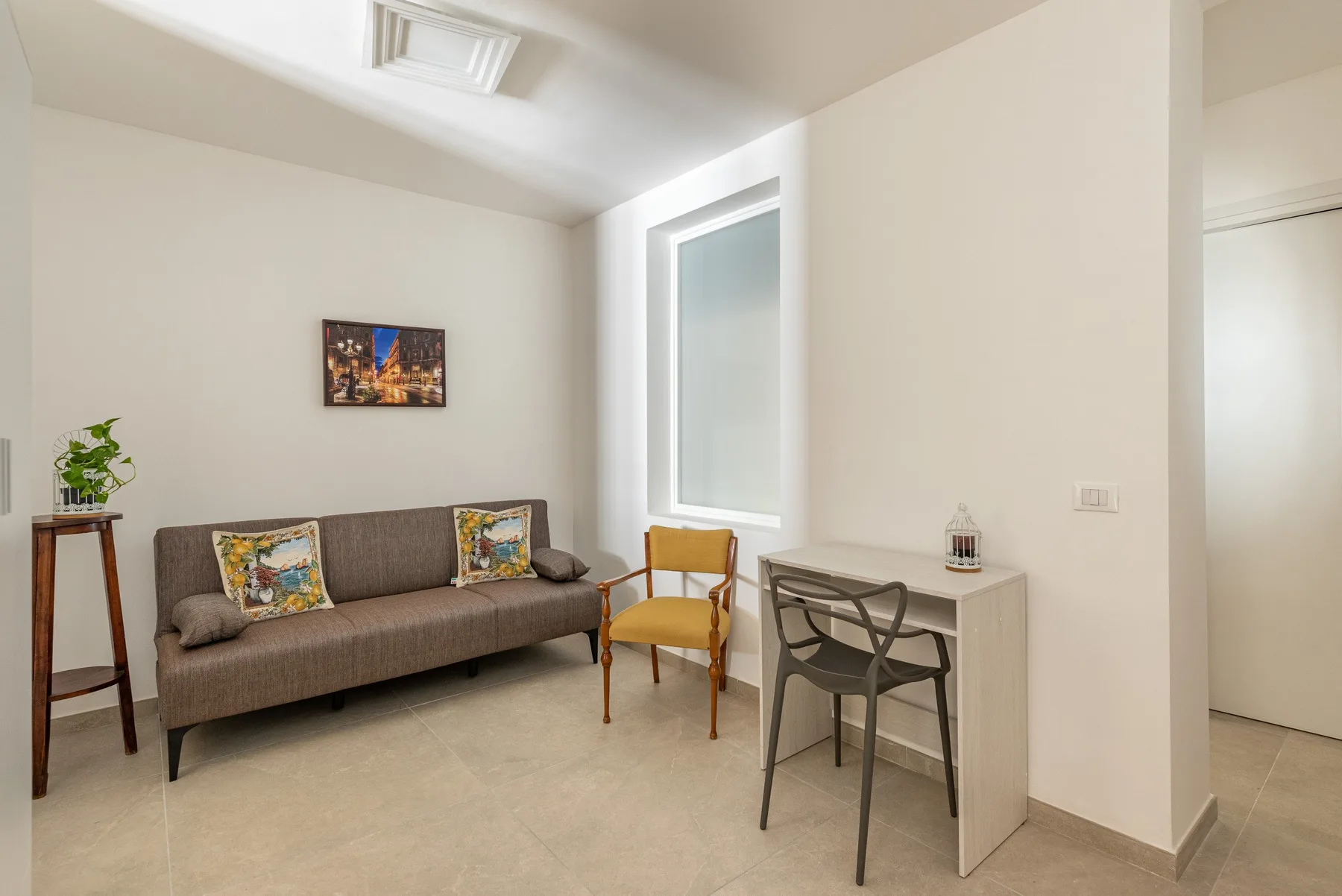 A bright sitting area with a sofa, chair, and small desk.
