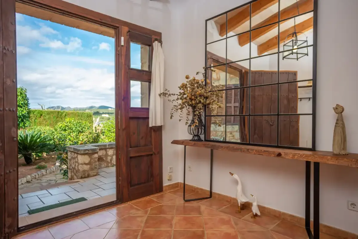 Una habitación con una puerta de madera abierta que da a un jardín y al campo.