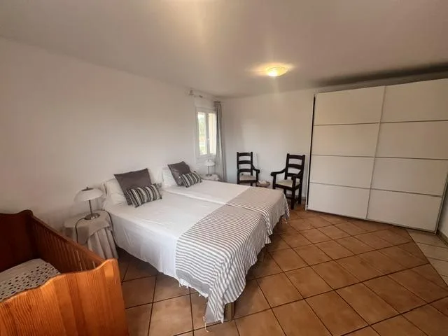 Un dormitorio con dos camas, sillas y un armario grande.