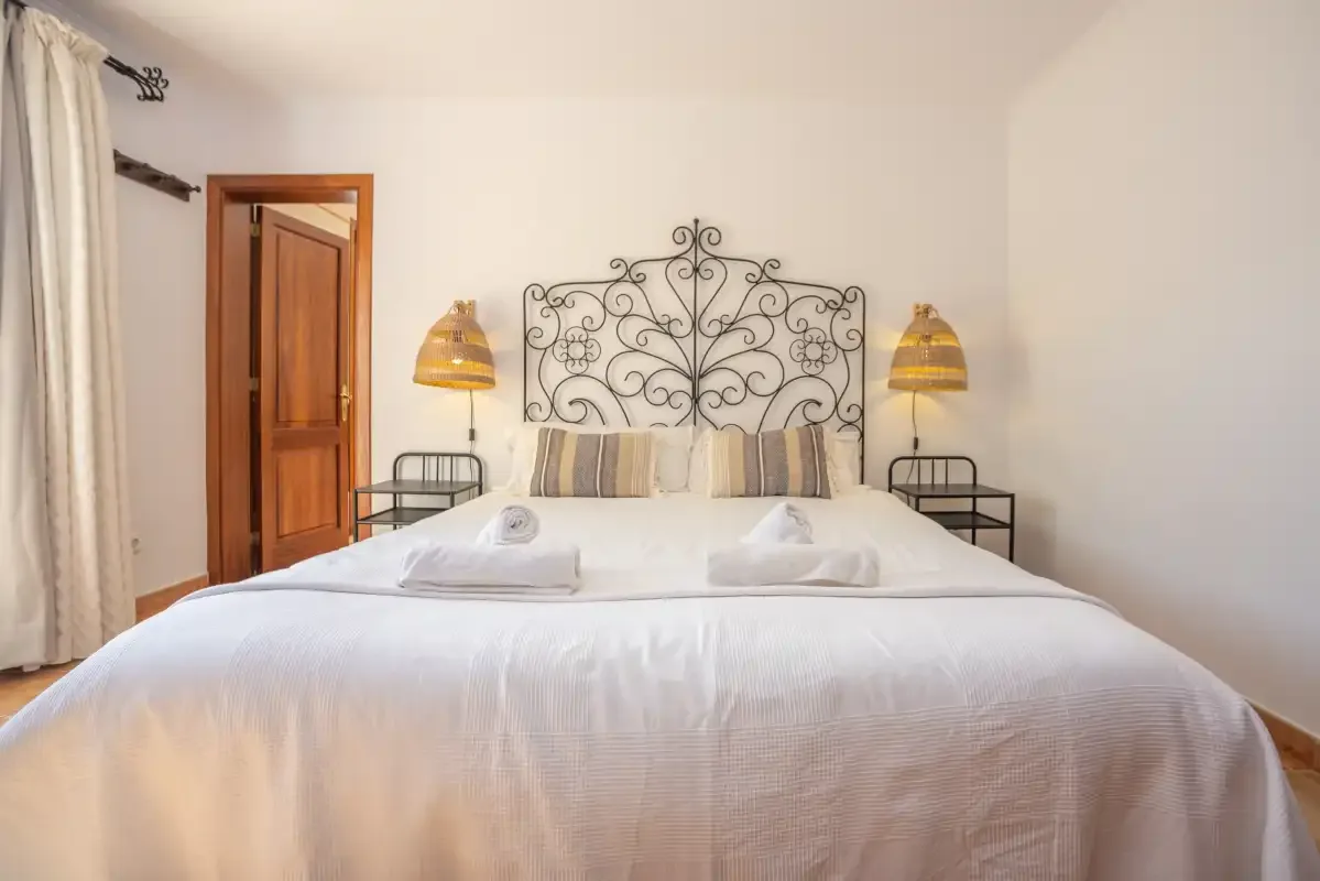 Un dormitorio con una cama bien hecha y un cabecero de metal ornamentado.