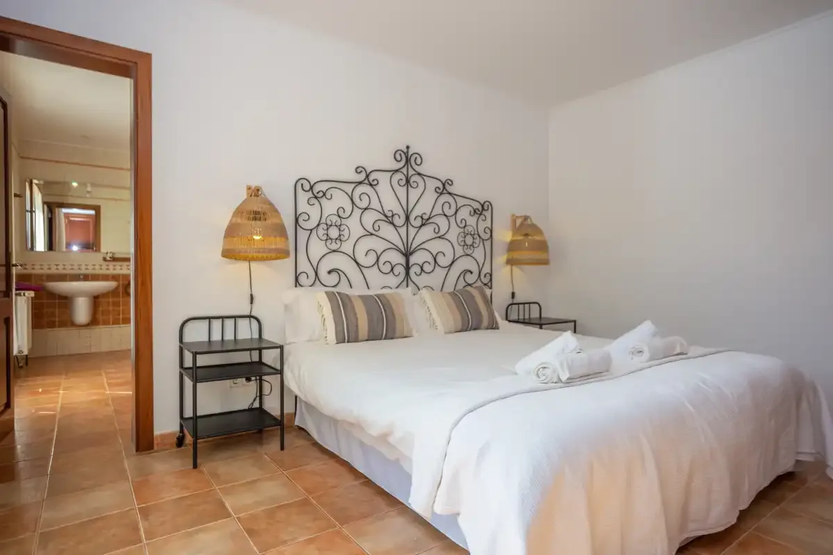 Un dormitorio con una cama, mesitas de noche y una puerta abierta.
