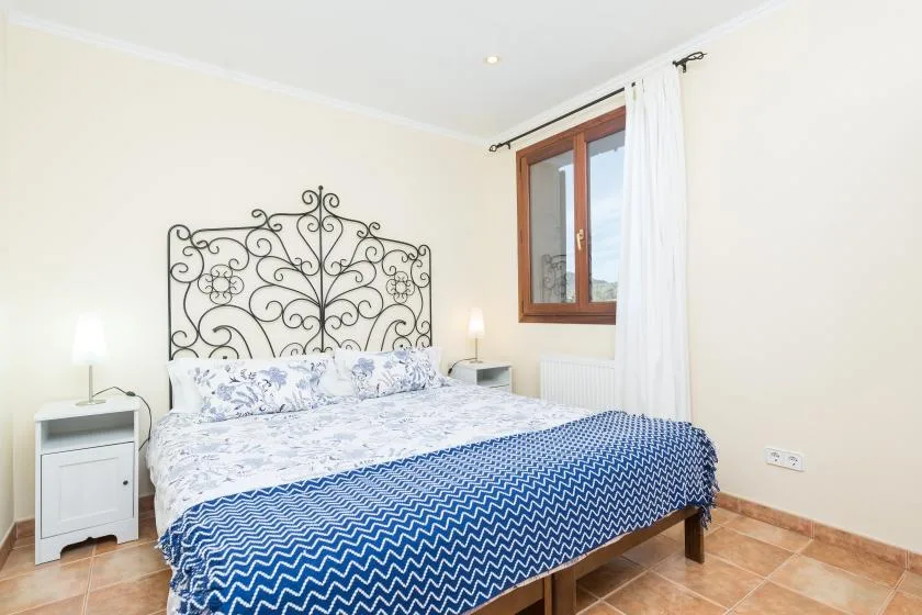 Un dormitorio con una cama doble, ropa de cama estampada y una ventana con cortinas.