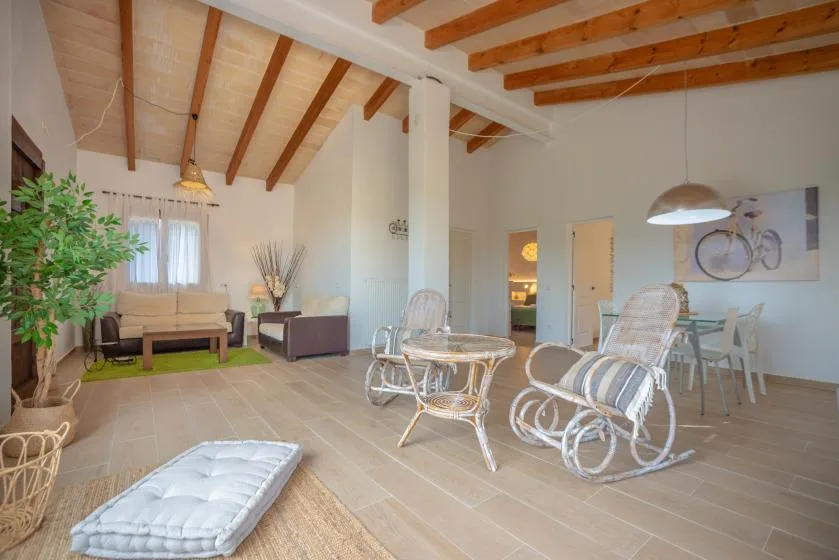 Una sala luminosa con asientos, una mesa de vidrio y vigas de madera a la vista.