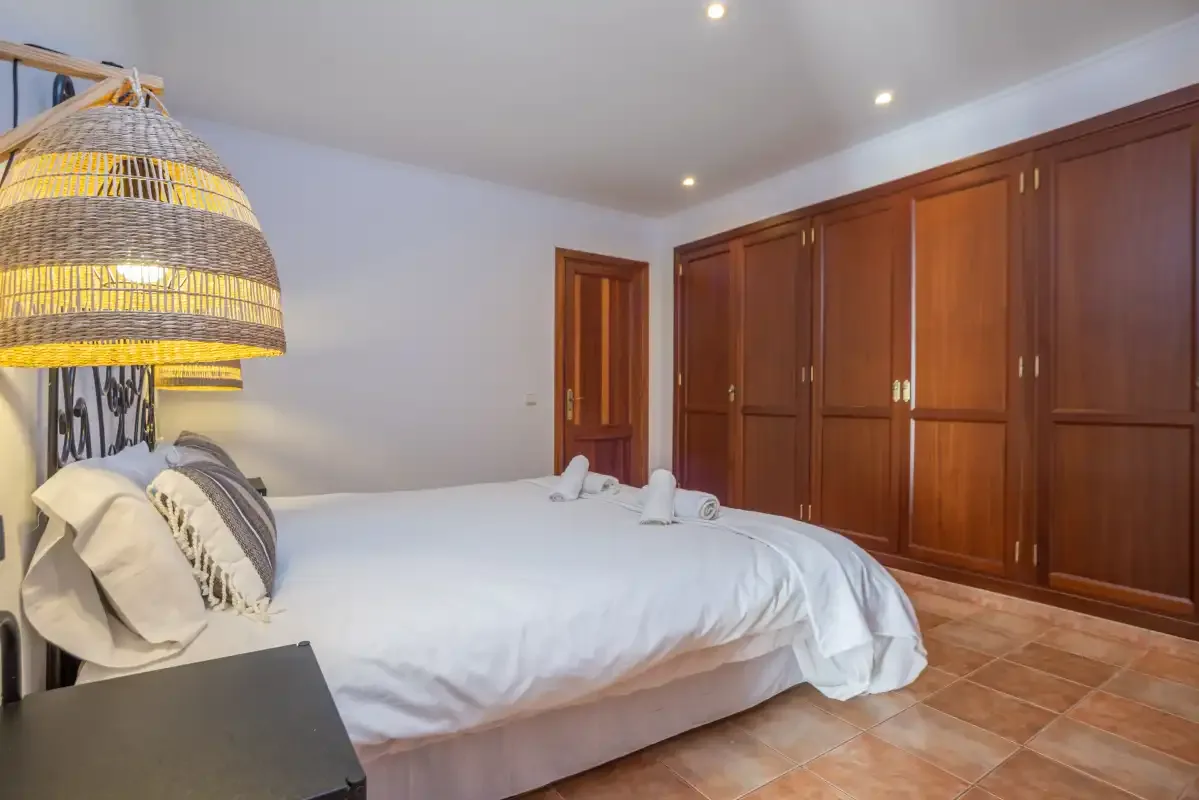 Un dormitorio con una cama grande junto a una fila de armarios de madera.