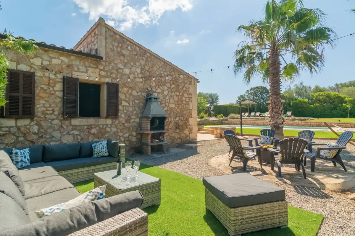 Una casa de piedra da a una zona de estar al aire libre con una palmera.