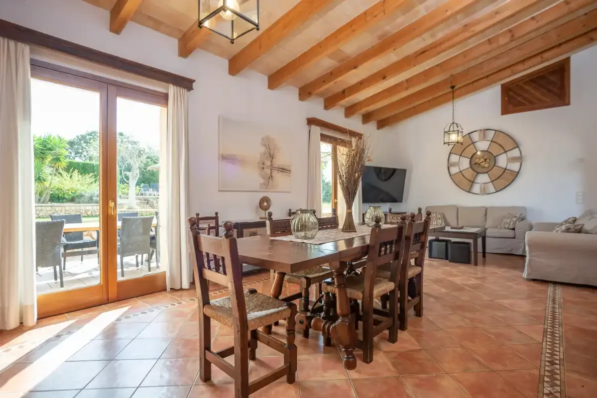 Sala de estar y comedor con asientos de madera y una puerta acristalada que da a un patio.