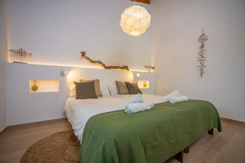 Un dormitorio con una cama vestida con sábanas blancas y una colcha verde.