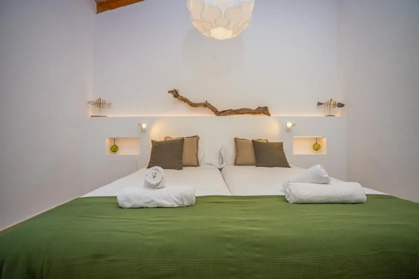 Un dormitorio con una cama doble, almohadas blancas y una colcha verde.