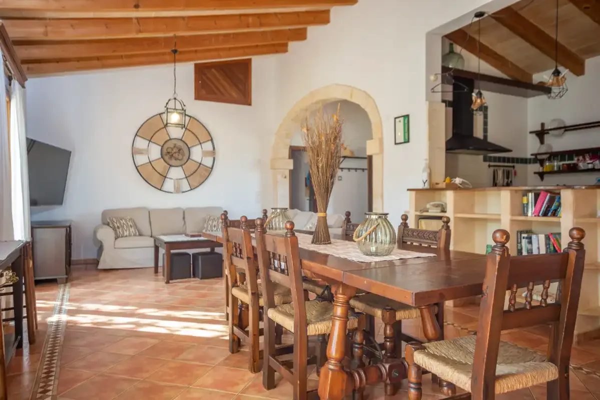 Una zona de comedor y estar con una mesa de madera, asientos y vigas vistas.