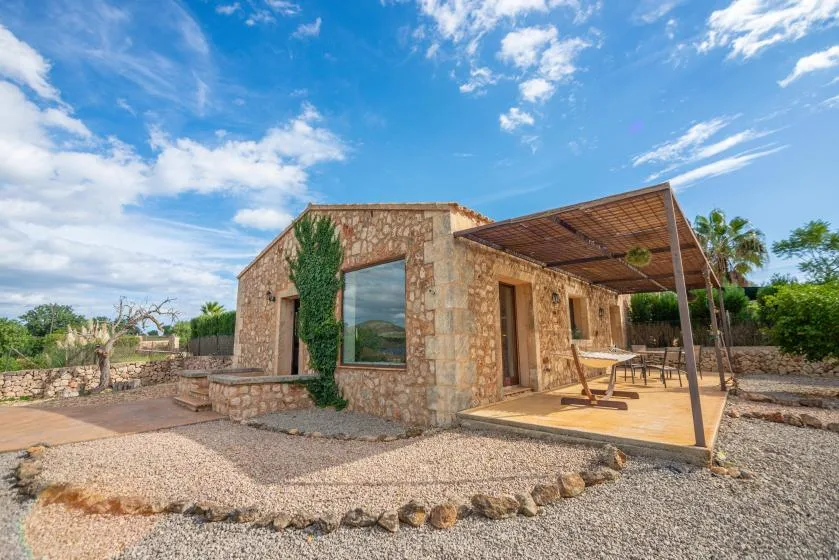 Una casa de piedra con una zona de estar exterior bajo un toldo.