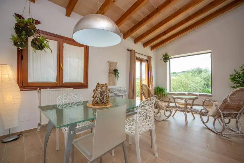 Un comedor luminoso con una mesa de cristal y asientos junto a una ventana grande.