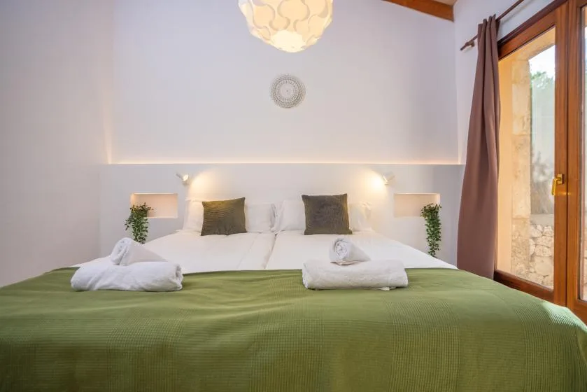 Un dormitorio con una cama grande cubierta con una manta verde y toallas dobladas.